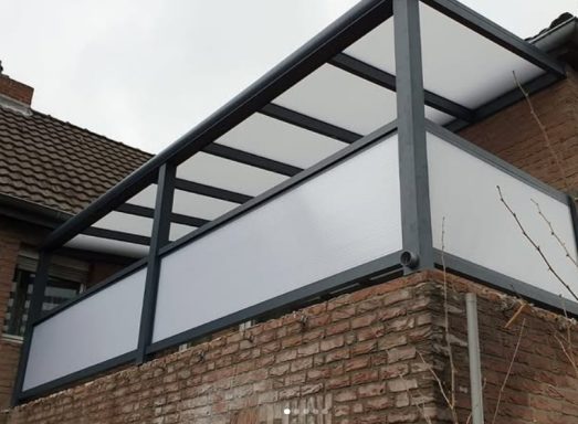 Moderne Überdachung eines Balkons mit grauem Rahmen und weißen Sichtschutzwänden.