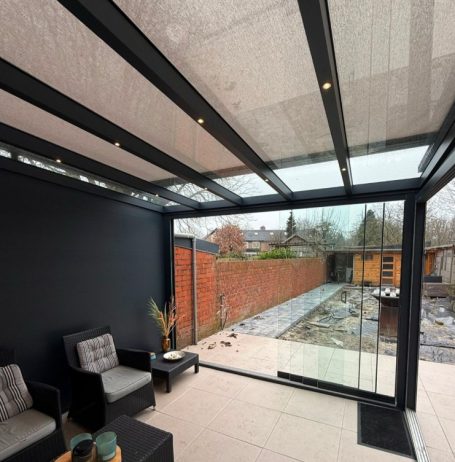 Moderne Patio-Überdachung mit Glaswänden und Blick auf den Garten.